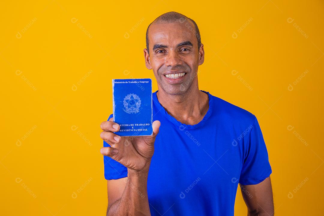 Homem brasileiro com trabalho documental e segurança social, (Carteira de Trabalho e Previdência Social) em fundo amarelo