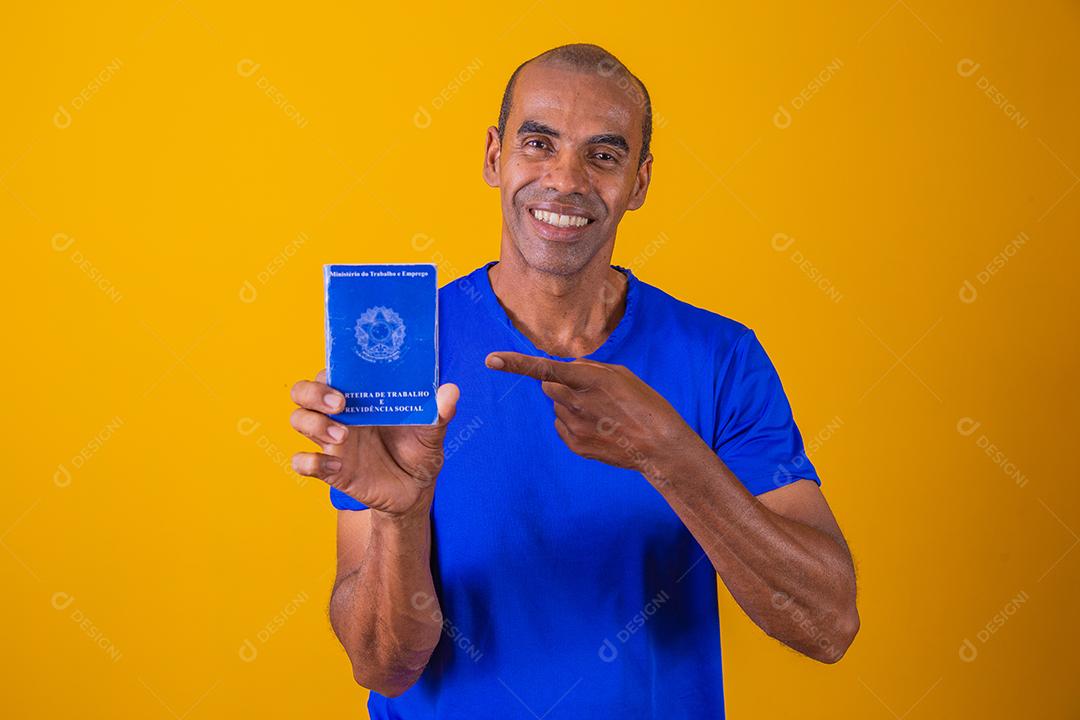 Homem brasileiro com trabalho documental e segurança social, (Carteira de Trabalho e Previdência Social) em fundo amarelo