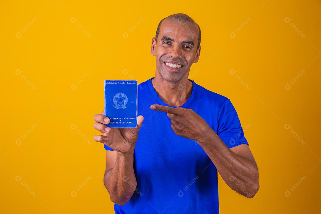 Homem brasileiro com trabalho documental e segurança social, (Carteira de Trabalho e Previdência Social) em fundo amarelo