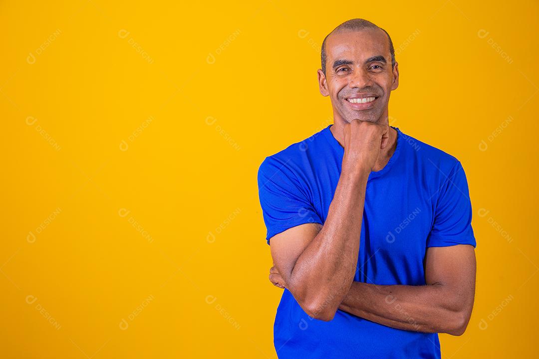 Homem afro mais velho sorrindo olhando para a câmera no fundo amarelo