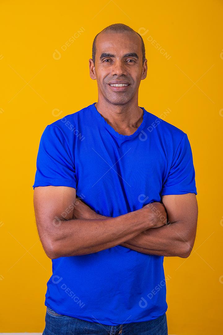 Homem negro mais velho cruzando os braços com confiança. otimista, feliz. Feliz. Homem afro com braços cruzados em fundo amarelo