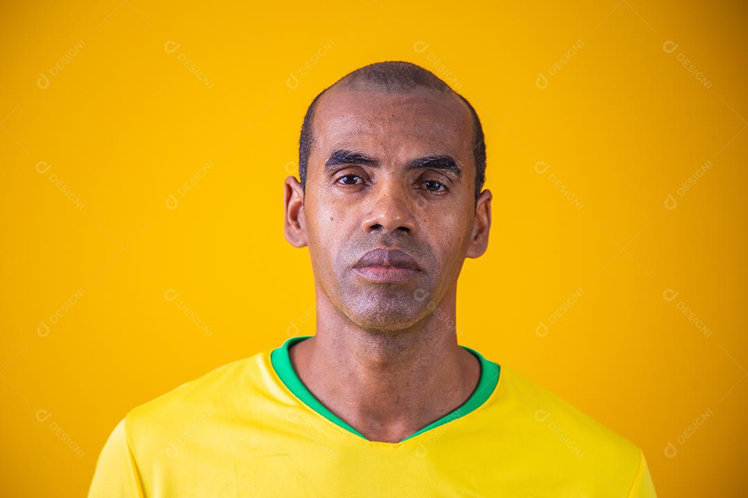 retrato de homem negro maduro com roupa amarela brasileira. Retrato de torcedor brasileiro em fundo amarelo