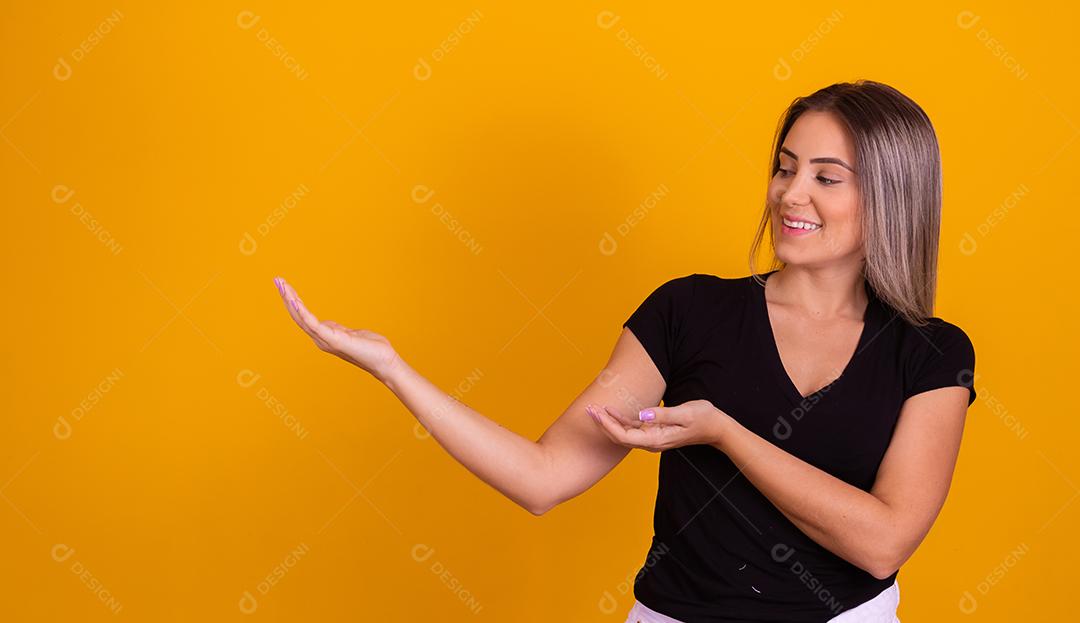 Mulher linda jovem apontando para lado sorridente sobre um fundo isolado amarelo