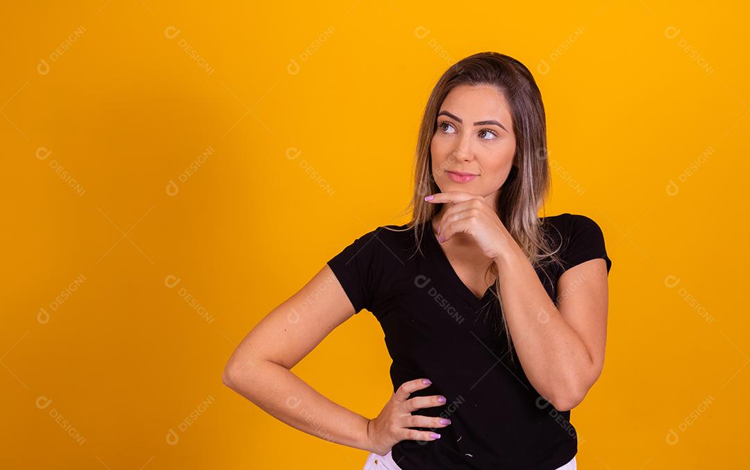 mulher loira pensativa em fundo amarelo