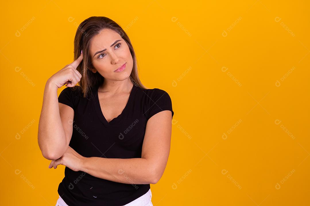 mulher loira pensativa em fundo amarelo