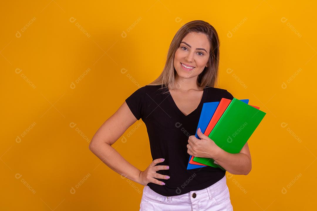 Aluna jovem com livros de volta para a escola sobre fundo amarelo