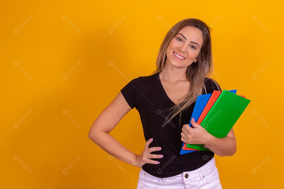 Aluna jovem com livros de volta para a escola sobre fundo amarelo