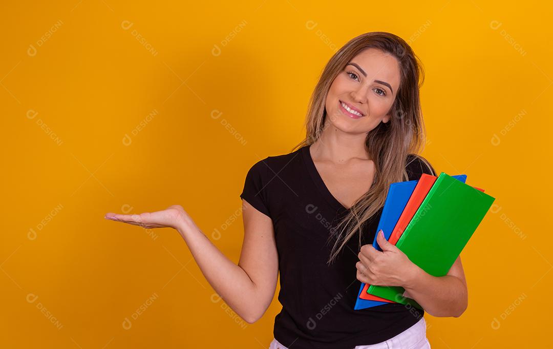 Aluna jovem com livros de volta para a escola sobre fundo amarelo