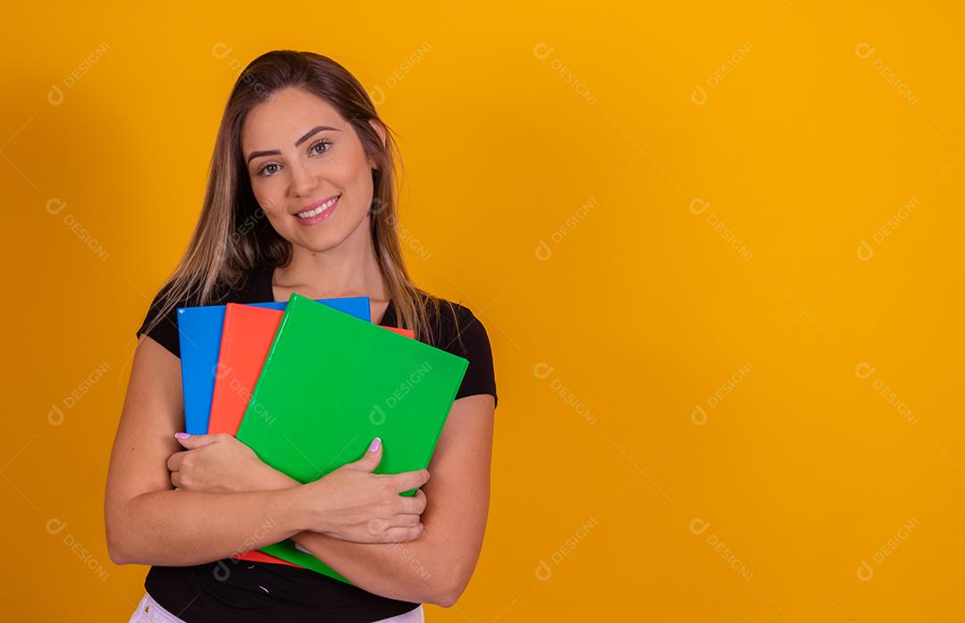 Aluna jovem com livros de volta para a escola sobre fundo amarelo