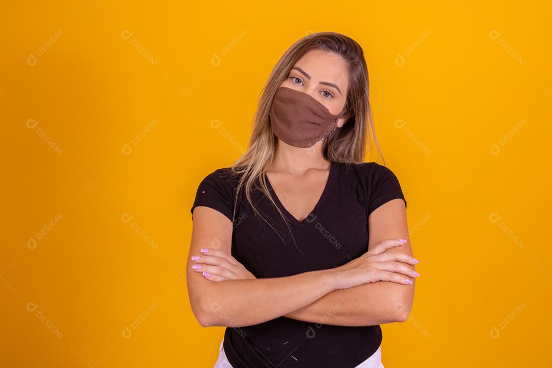 Mulher loira usando mascara, blusa preta fazendo gestos com as mãos