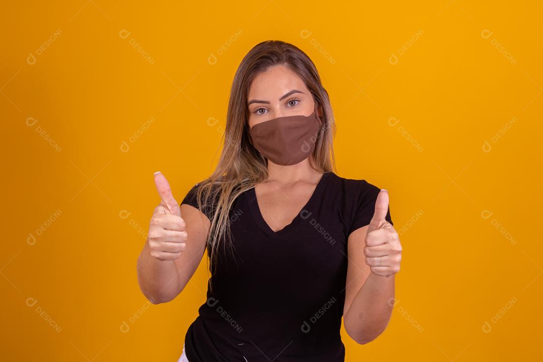 Mulher loira usando mascara, blusa preta fazendo gestos com as mãos