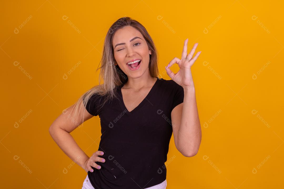 Mulher loira usando uma blusa preta fazendo gestos com as mãos