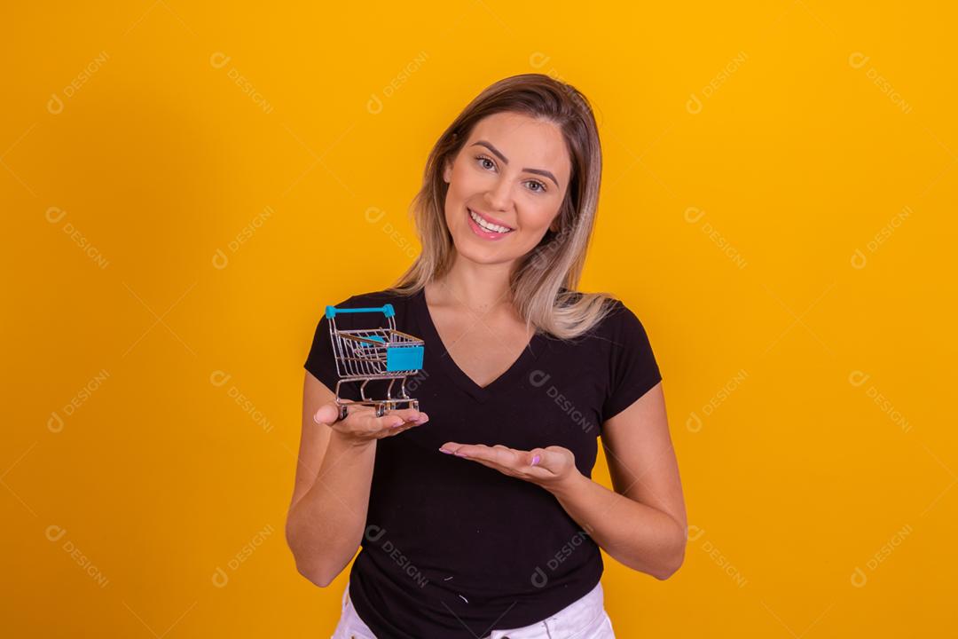 Mulher loira usando uma blusa preta segurando um carrinho de supermercado