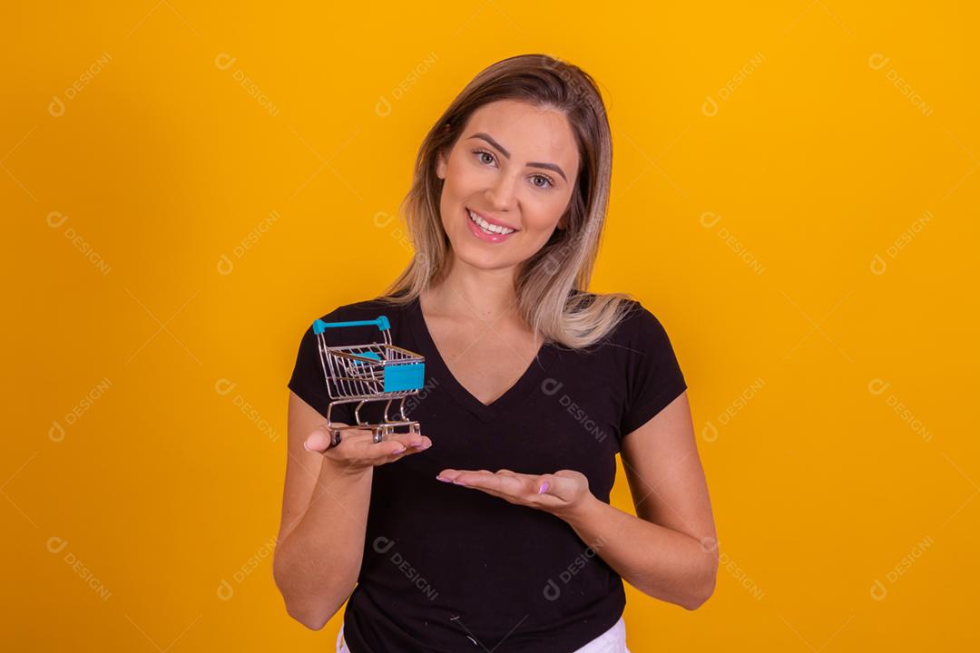 Mulher loira usando uma blusa preta segurando um carrinho de supermercado