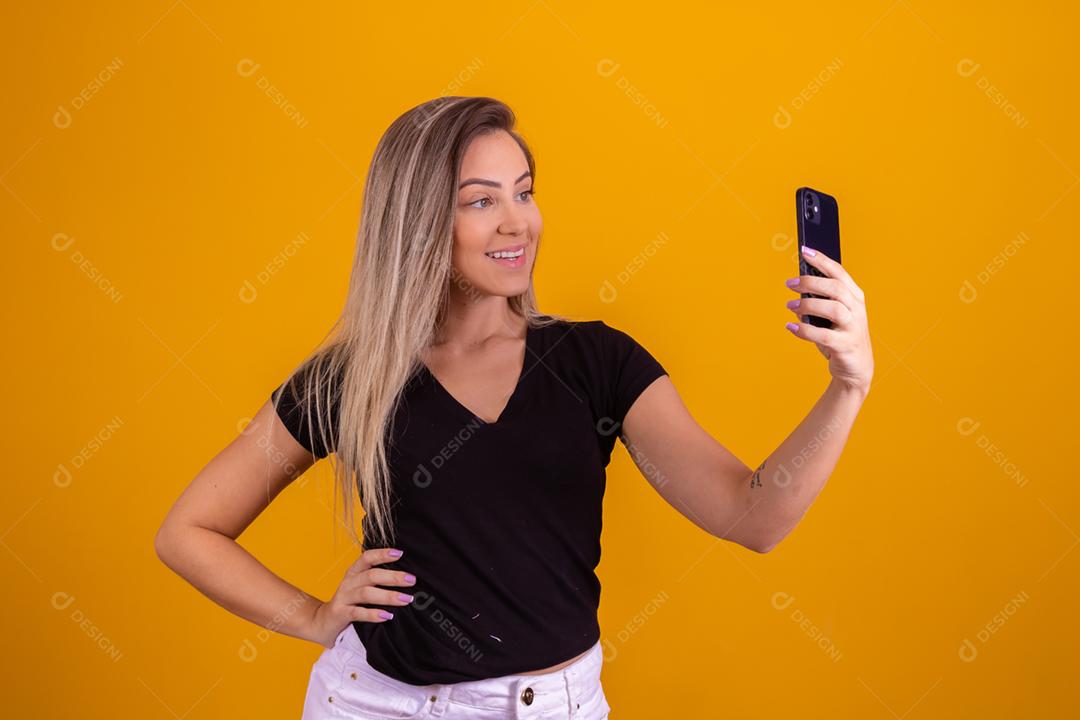 Mulher loira usando uma blusa preta segurando um celular