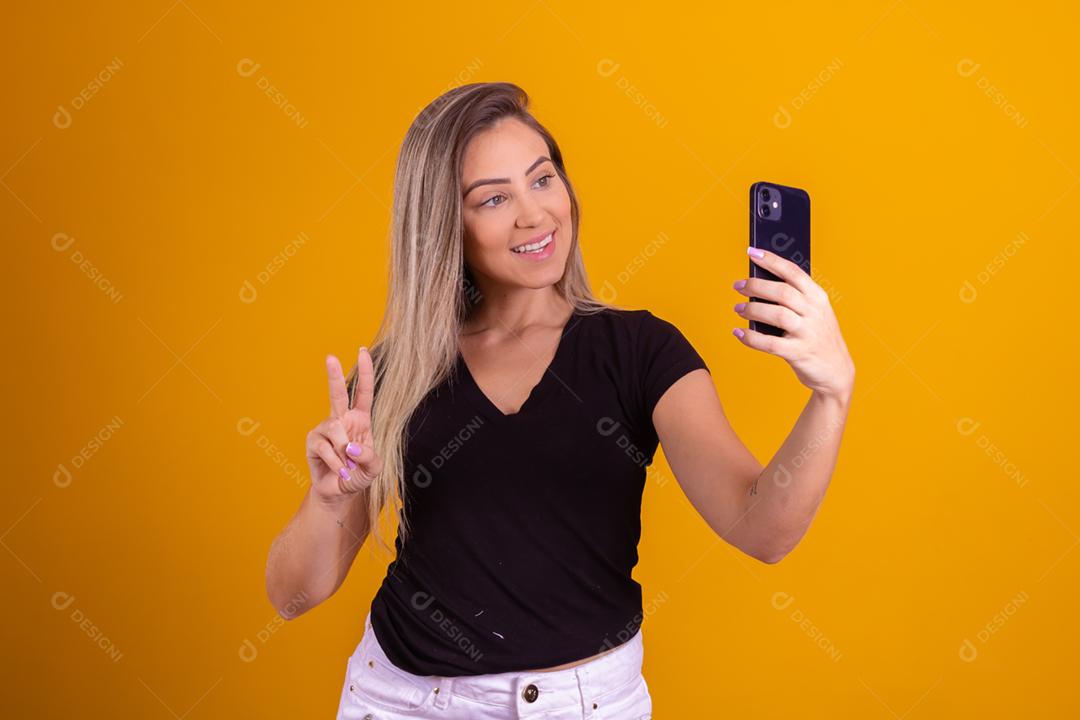 Mulher loira usando uma blusa preta segurando um celular