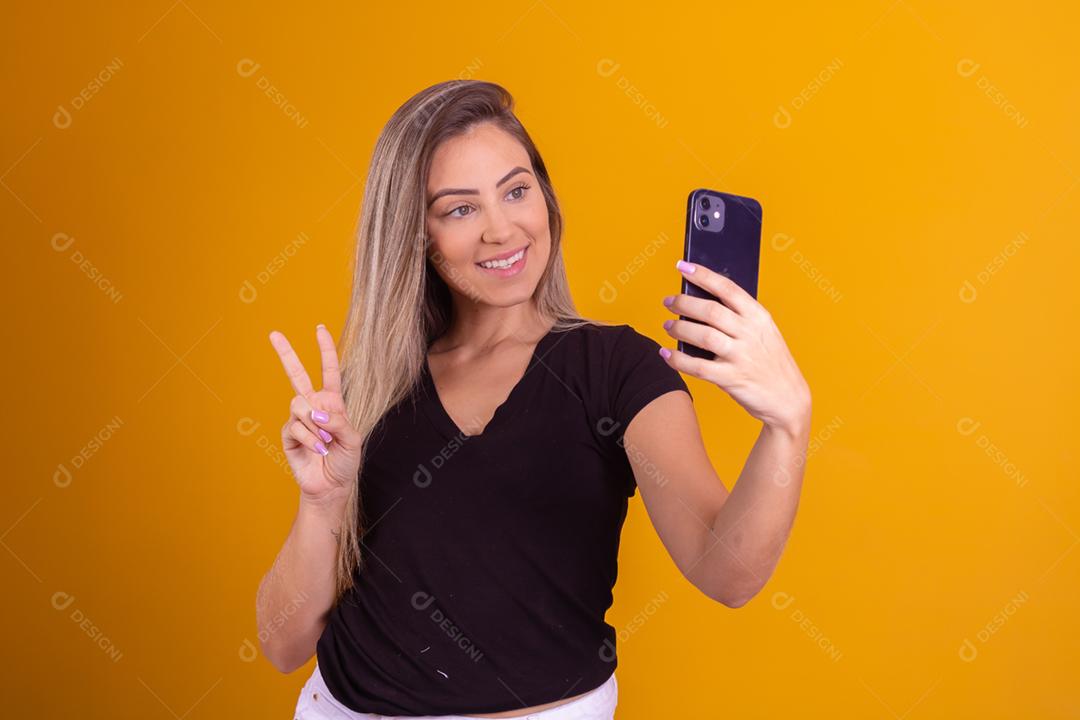 Mulher loira usando uma blusa preta segurando um celular