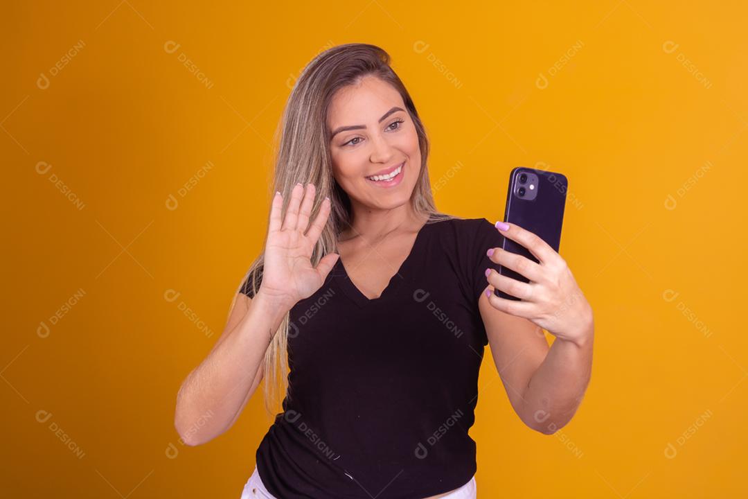 Mulher loira usando uma blusa preta segurando um celular