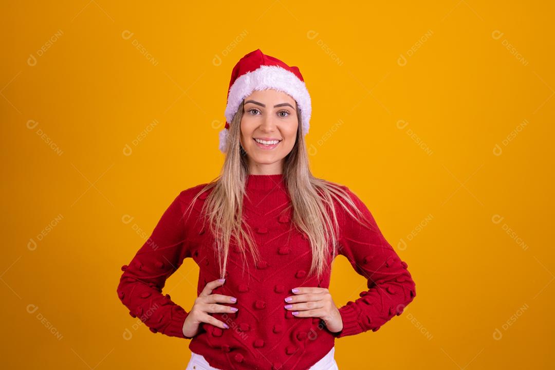 Mulher loira com um chapeu de papai noel em fundo amarelo