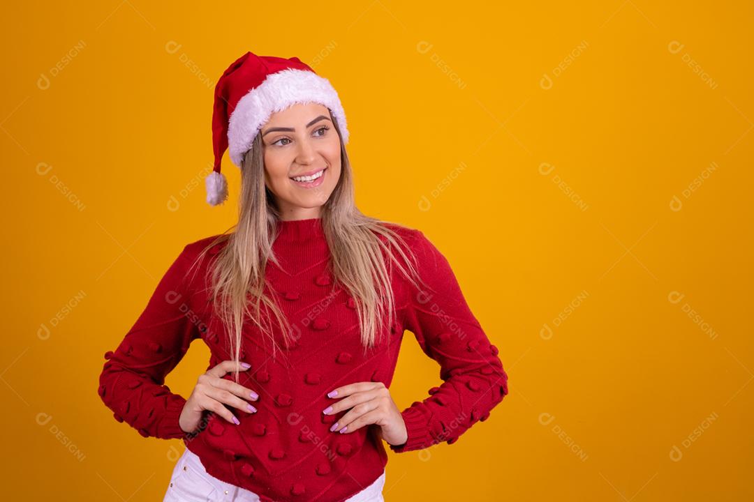 Mulher loira com um chapeu de papai noel em fundo amarelo