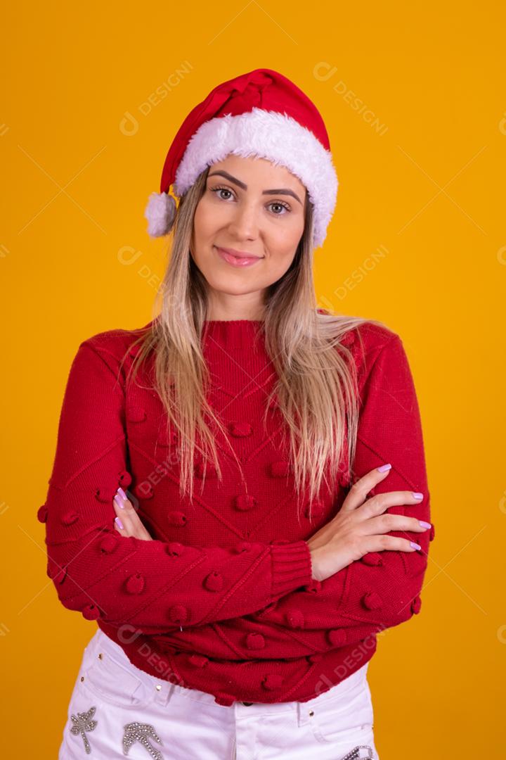 Mulher loira com um chapeu de papai noel em fundo amarelo