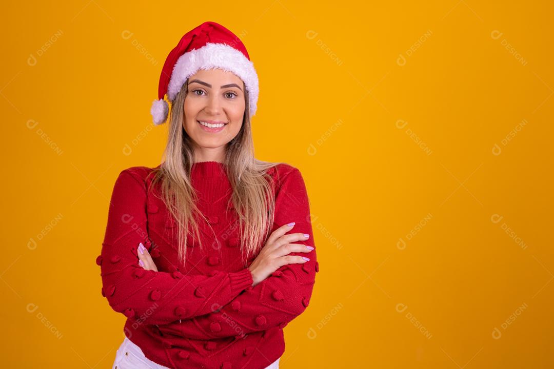 Mulher loira com um chapeu de papai noel em fundo amarelo