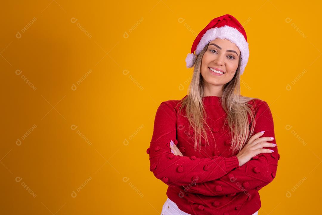 Mulher loira com um chapeu de papai noel em fundo amarelo