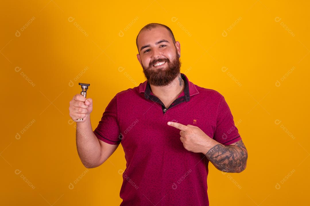 homem ruivo de barba usando uma camisera vermelha se barbeando