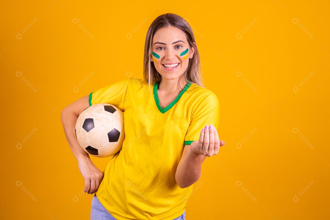 Mulher jovem torcedora brasileira com uma bola de futebol