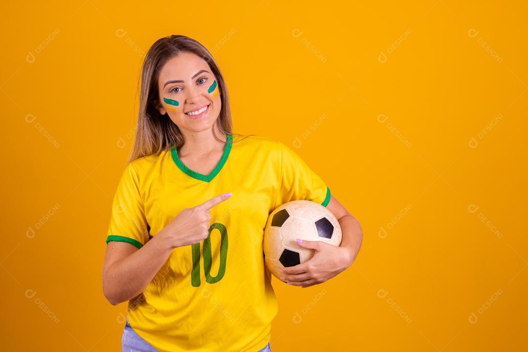 Mulher jovem torcedora brasileira com uma bola de futebol