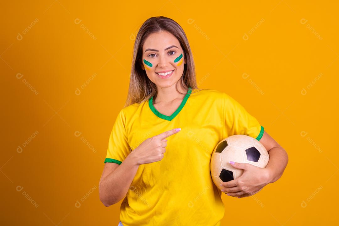 Mulher jovem torcedora brasileira com uma bola de futebol
