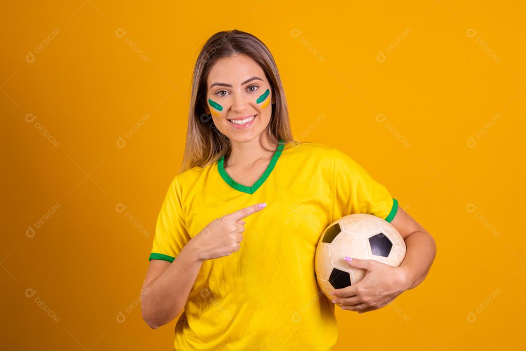Mulher jovem torcedora brasileira com uma bola de futebol