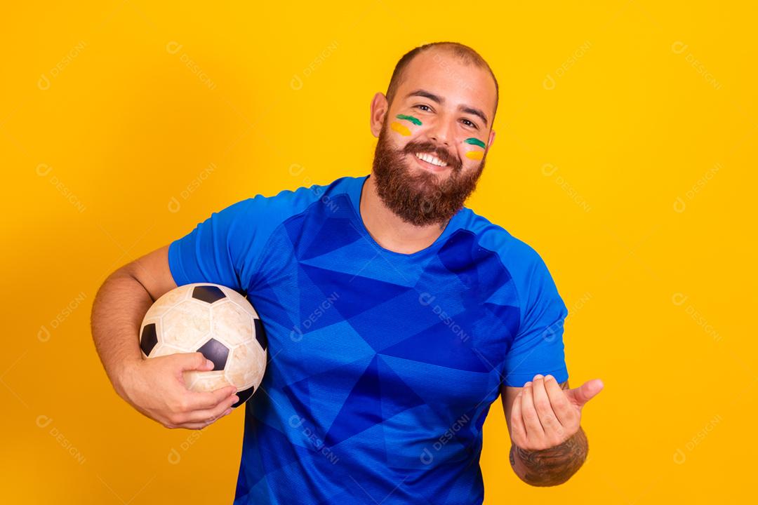 Homem jovem torcedor brasileiro com uma bola de futebol