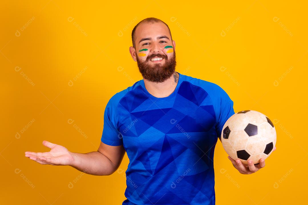 Homem jovem torcedor brasileiro com uma bola de futebol