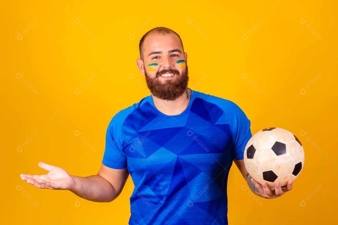 Homem jovem torcedor brasileiro com uma bola de futebol