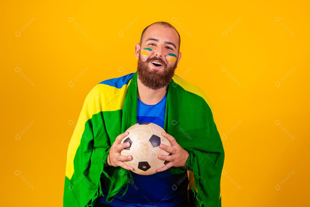 Homem jovem torcedor brasileiro com uma bola de futebol