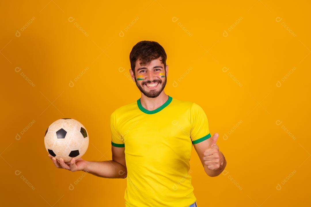 Homem jovem torcedor brasileiro com uma bola de futebol