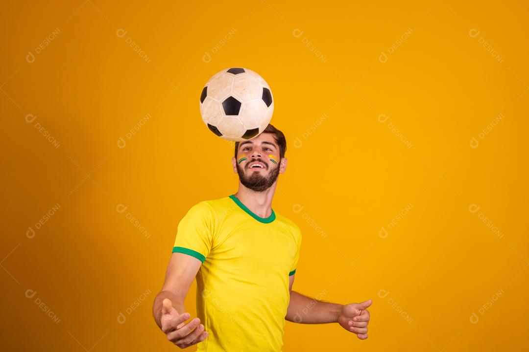 Homem jovem torcedor brasileiro com uma bola de futebol