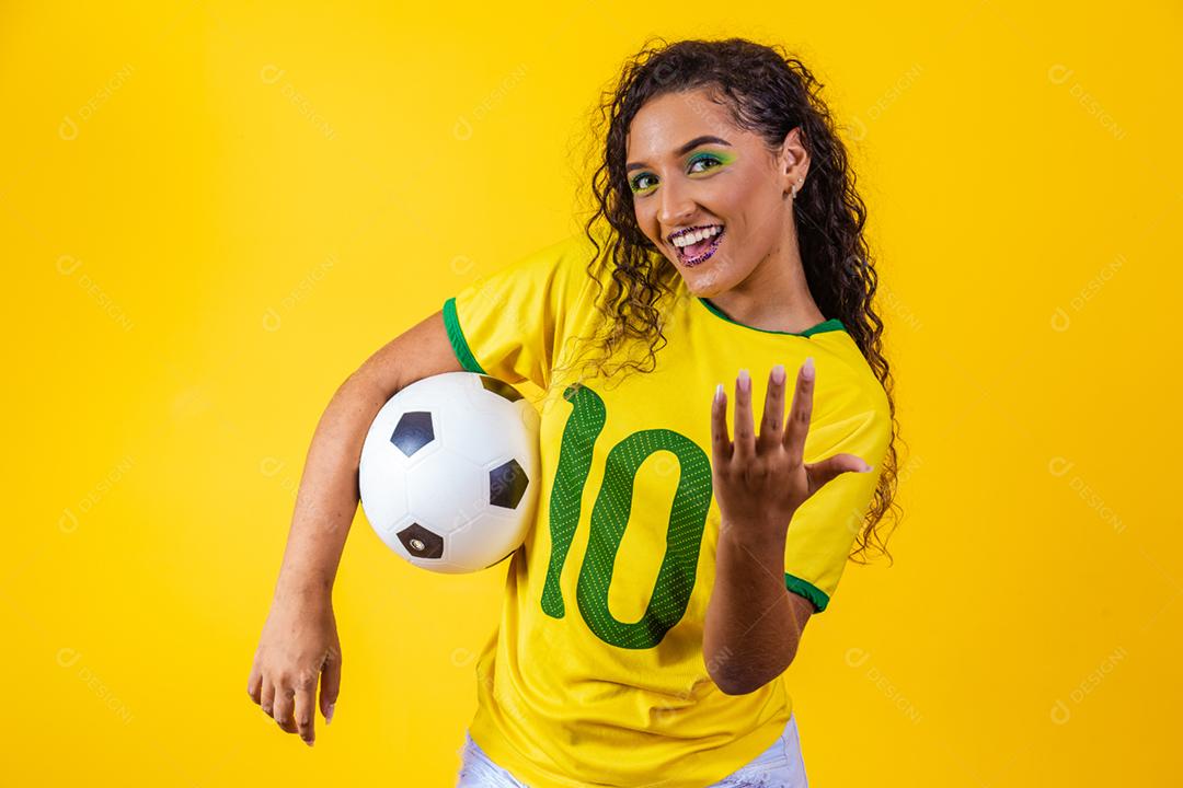 bela torcedora brasileira com uma bola de futebol em amarelo