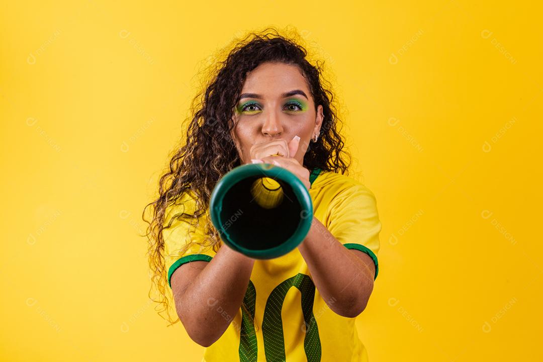 Líder de torcida brasileira jovem afro com uma vuvuzela em amarelo