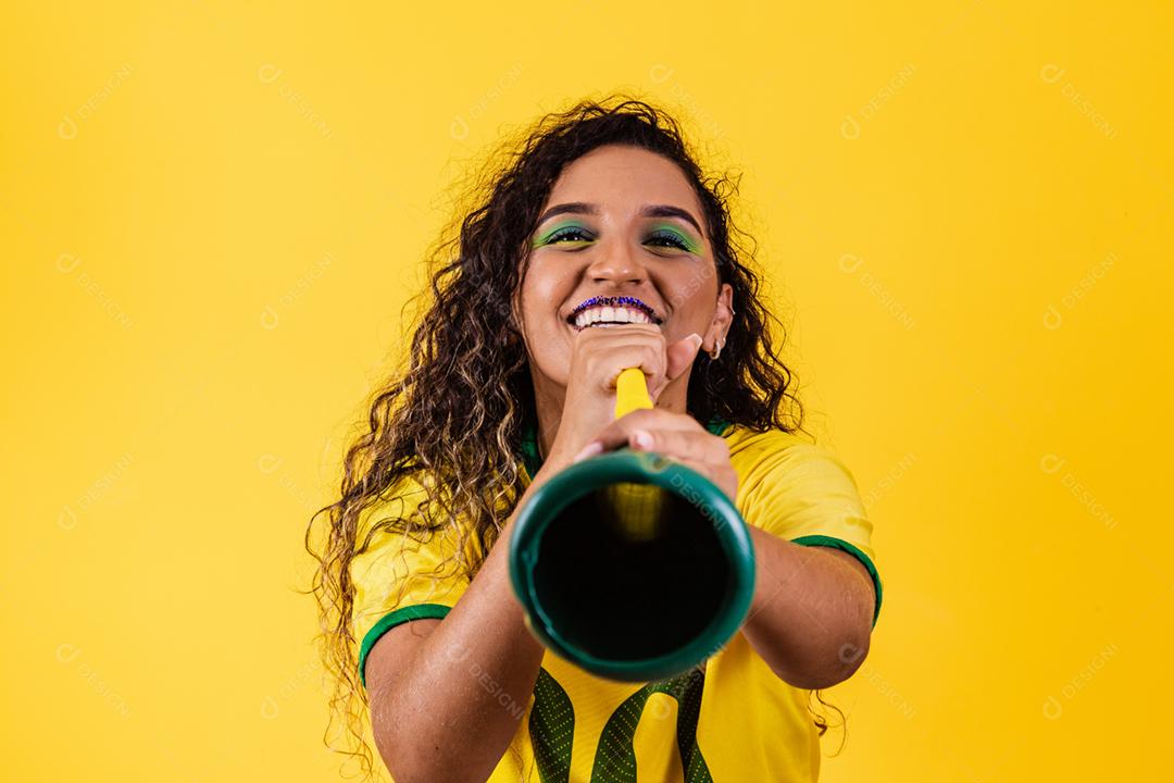 Líder de torcida brasileira jovem afro com uma vuvuzela em amarelo