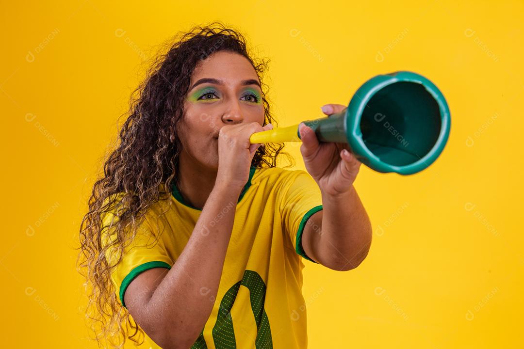 Líder de torcida brasileira jovem afro com uma vuvuzela em amarelo