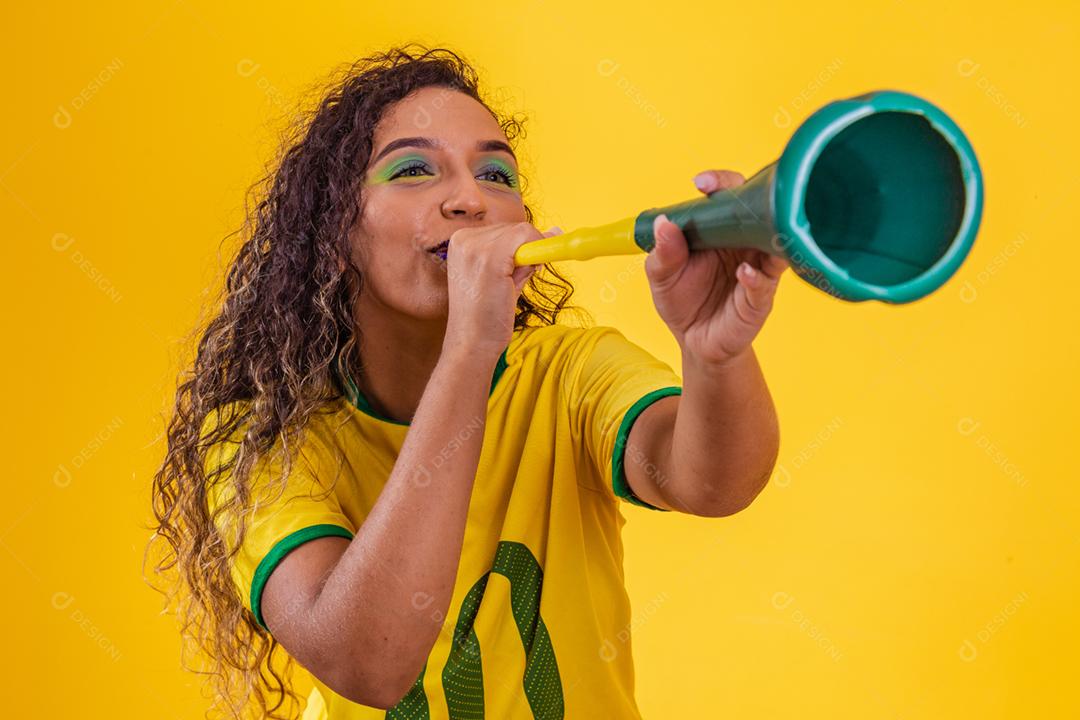 Líder de torcida brasileira jovem afro com uma vuvuzela em amarelo