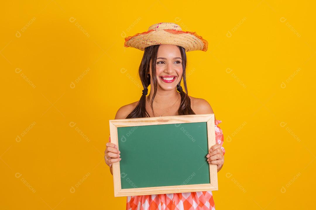 Jovem mulher segurando um quadro-negro com espaço de cópia. Festa junina.