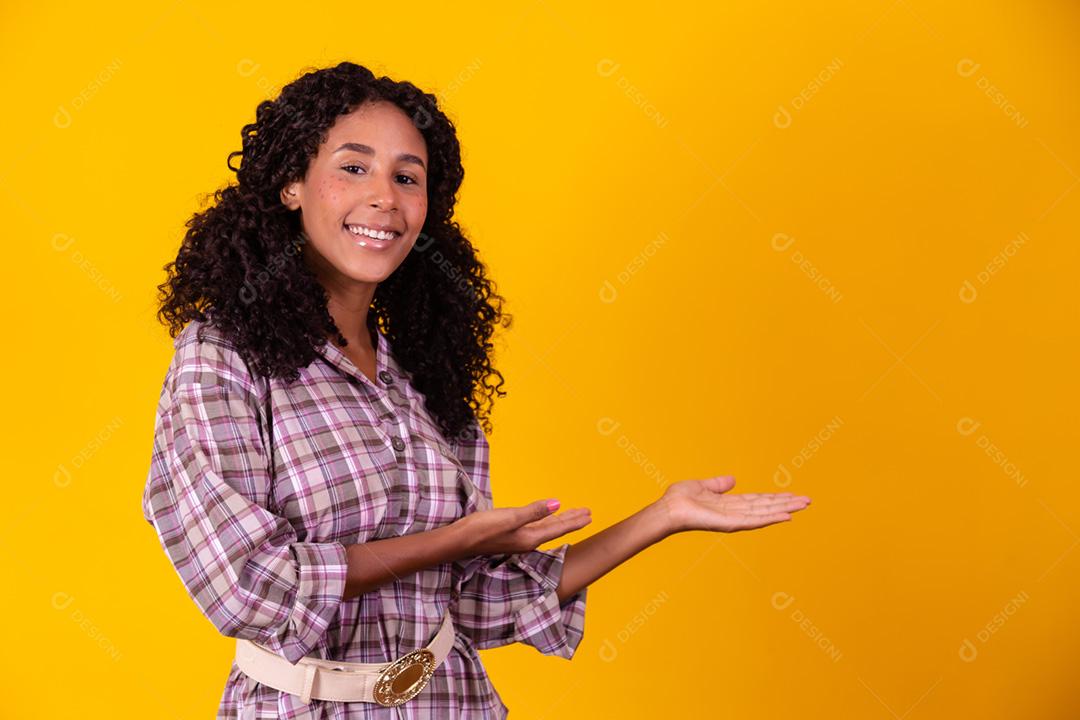 Mulher afro vestida com roupas de festa junina e cabelo amarrado por maria