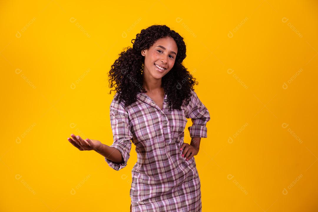 Mulher afro vestida com roupa de festa junina apontando para o lado.