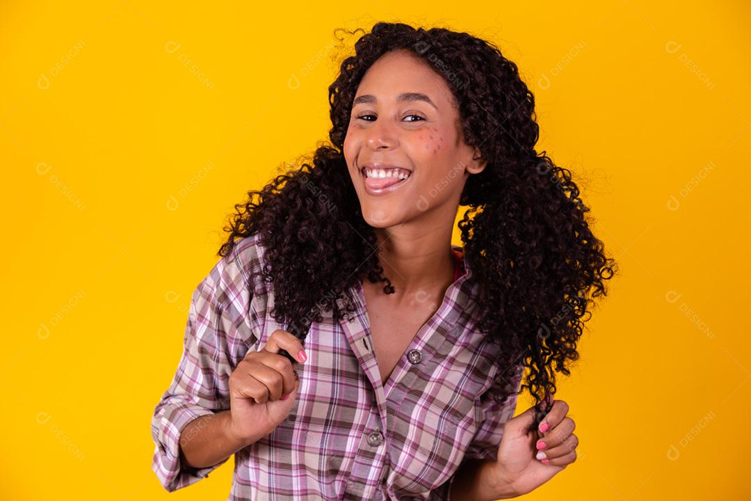 Mulher afro vestida com roupas de festa junina e cabelo amarrado por maria