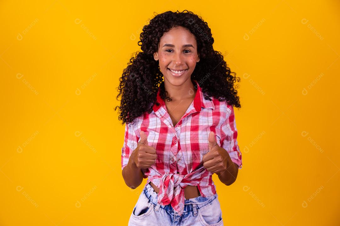 Mulher afro vestida com roupa de festa junina apontando para o lado.