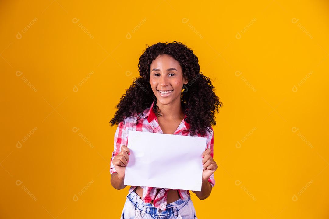 Mulher negra com roupa de festa junina segurando um cartão em branco para texto