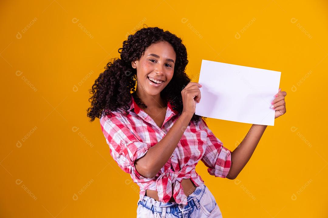 Mulher negra com roupa de festa junina segurando um cartão em branco para texto